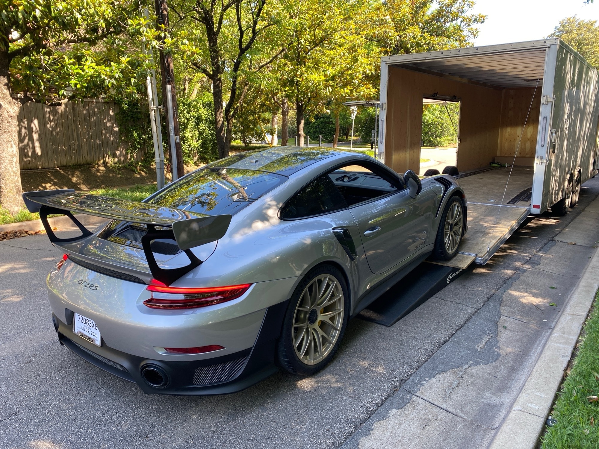 A silver Porsche 911 GT2 RS being loaded into an enclosed transport trailer